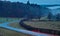 Countryside road into misty forest, traffic blur