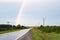 Countryside road wet with rain and part of the rainbow over the road