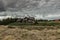 Countryside scene with wooden house and cloudy sky on background. Farm house surrounded by trees and fields.Lonely tourist house