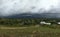 countryside surrounded by overcast mountains and forest