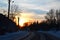 Countryside winter road between little houses below saturated sunset sky in winter evening. Beautiful winter landscape