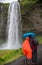 Couple admiring Seljalandsfoss waterfall on a rainy day. Seljalandsfoss.