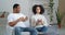 Couple afro american family young people husband and wife sitting on couch in cozy living room drinking hot tea coffee