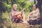 Couple of alternative aged older traveler stay sitting down in a vineyard with the luggage and playing an ukulele acoustic guitar