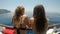 Couple of attractive young women in bathing suit enjoying summer trip on sailing ship relaxing and chatting -