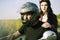 Couple on the background of the field rides a motorcycle. A man in a helmet rolls his girlfriend in a safety helmet. Road safety.