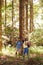 Couple With Backpacks Hiking Or Walking Through Woodland Countryside