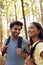 Couple With Backpacks Hiking Or Walking Through Woodland Countryside