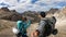 A couple with backpacks and sticks hiking on a narrow path in Italian Dolomites. There are sharp and steep mountains around.