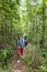 Couple With Backpacks Trekking On Forest Path, Young Man And Woman Holding Hands Walk On Hike Tourists