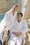 Couple In Bathrobe Sitting On Chair By Pool