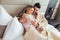 Couple in bathrobes lying on bed in hotel room