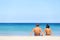 Couple on beach sitting in sand looking at sea