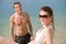 Couple on beach - sunbathing in swimsuit by sea