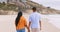 Couple, beach and walking while holding hands outdoor and happy together on vacation or holiday. Man and woman at sea