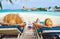 Couple at beach on wooden sun bed loungers