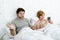 Couple in bed husband frustrated upset and unsatisfied while his internet addict wife is using mobile phone