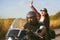 Couple of bikers ride across the field. A man drives a motorcycle, a girl listens to music with headphones on the road. The joy of