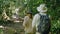 couple biologist on a forest walk collecting data is using binoculars to look into the treetops