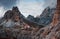 A couple of buildings between the great Paternkofel mountains with fog at the top near the edge of the hill