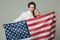 Couple on calm faces holds flag of USA. Guy and girl proud to be americans, grey background. Language school concept