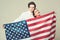 Couple on calm faces holds flag of USA. Guy and girl proud to be americans, grey background. Language school concept