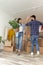 Couple carrying cardboard boxes and doing high five while moving in together