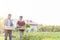 Couple carrying vegetables in crate while walking in farm against sky