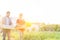 Couple carrying vegetables in crate while walking in farm against sky with yellow lens flare in background