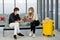 Couple Caucasian lovers man and woman with mask sit on chair with social distance and discuss together in airport during flight