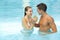 Couple celebrating with sparkling wine in pool