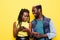 Couple changes their phones. Portrait of an excited young afro american couple holding mobile phones isolated on yellow background