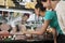 Couple Choosing Cheese From Display Cabinet While Saleswoman