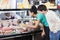 Couple Choosing Product From Display Cabinet While Salesman Assi