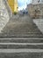 Couple Climbing Ancient Stone Rustic Grey Staircase and Old Rustic Textured Wall Symbolizing Challenge and Progress