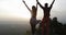 Couple coming to mountain top raising hands back rear view, man and woman enjoy sunrise landscape