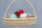 Couple cups of tea or coffee and two red roses hanging in a wooden rattan basket on blue background. Still life concept.