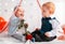 A couple of cute babies posing on a white background decorated with hearts. A happy girl holds a rose in her hands. Valentine`s