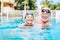 Couple of cute seniors and pensioners in the water of the pool having fun and enjoying together - two mature people in love