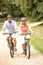Couple Cycling In Countryside Wearing Safety Helme