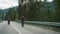 Couple cycling mountain road together in forest landscape. Tourists riding bike.