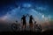 Couple cyclists with mountain bikes at night under starry sky