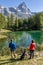 A couple with a dog admires the beautiful landscape of Lago Blu or Layet, which mirrors Mount Cervino, Aosta Valley, Italy