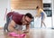 Couple doing chores polishing floors and putting dishes in dishwasher