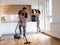 Couple doing chores together vacuuming and cleaning dust in the kitchen