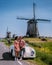 couple doing a road trip with an old vintage sport car by the Dutch windmill village Schermerhorn