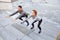 Couple doing squats on city street stairs