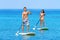 Couple Doing Stand Up Paddleboarding On Ocean