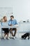 Couple drinking coffee and talking by kitchen table with laptop while their