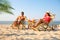 Couple with drinks resting on sunny beach